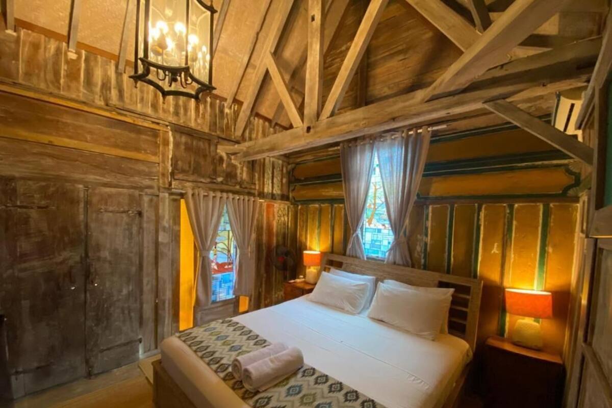 Une pièce en bois avec un lit, des rideaux et un lustre.