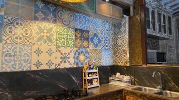 Een koelkast, een kookplaat, een vaatwasser, kookgerei, borden en bestek