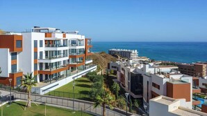 Un complexe d’appartements moderne composé de plusieurs immeubles, doté de balcons et offrant une vue sur la mer.