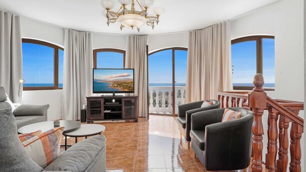 Un salon spacieux doté d’une grande télévision, de sièges confortables et d’un balcon offrant une vue agréable.