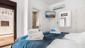 Une chambre d’hôtel équipée d’un lit, d’une télévision, d’un système de climatisation et offrant une vue sur la mer par une fenêtre.