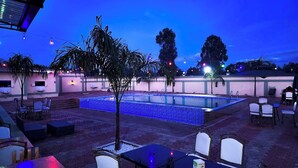 An outdoor pool area with seating and palm trees. - Derby Place Lounge Karatina (Karatina)