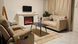 A living room with a fireplace, a sofa, a coffee table, and a TV. - Derby Place Lounge Karatina (Karatina)