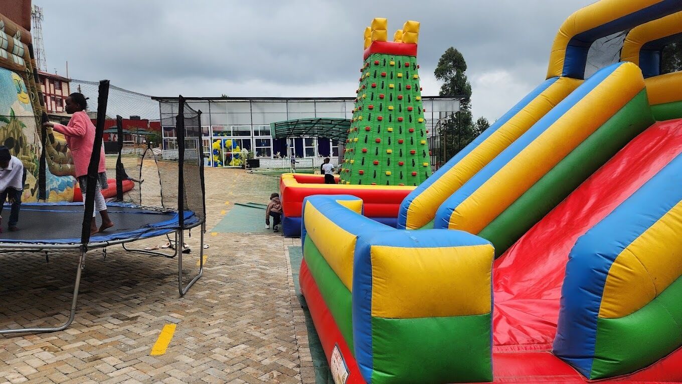 An outdoor play area with inflatable slides and a climbing structure.