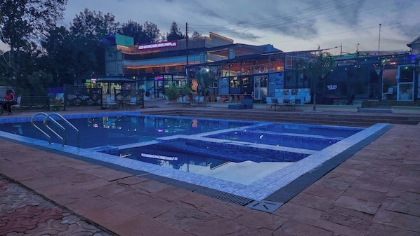 A swimming pool with a tiled deck, surrounded by a building with a sign indicating it is a hotel. - Derby Place Lounge Karatina (Karatina)