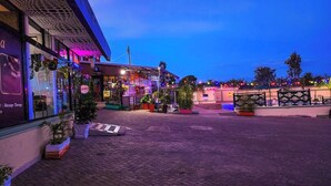 A paved courtyard with potted plants and a building with a massage therapy sign. - Derby Place Lounge Karatina (Karatina)