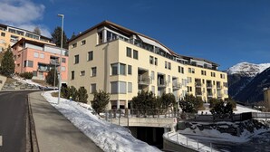 Ein mehrstöckiges Hotel mit Balkonen, einer Fußgängerbrücke und einem verschneiten Berg im Hintergrund.