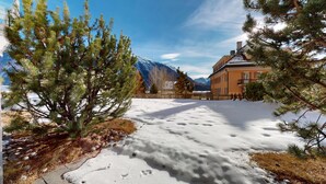 Schneebedeckte Landschaft mit einem Haus und Bergen im Hintergrund.