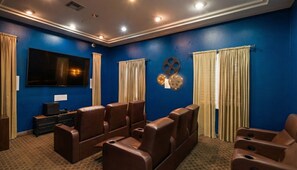 A home theater room with blue walls, a large flat-screen TV, leather reclining chairs, and a carpeted floor. - 1 Bedroom Sunset Escape In Marina Del Rey (Marina del Rey)