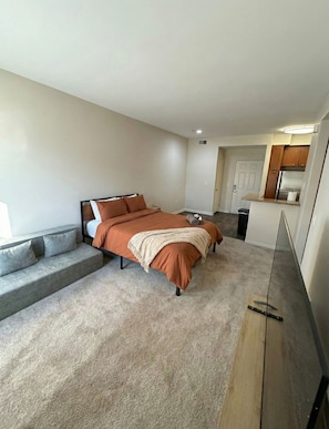A modern bedroom with a bed, a grey sofa, and a small kitchenette. - 1BR Haven In Marina Del Rey - Venice Beach - Resort Amenities (Marina del Rey)