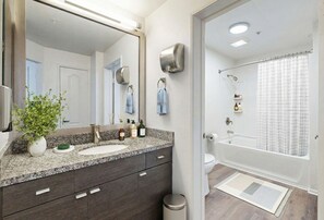 A bathroom with a granite countertop, a sink, a mirror, a towel rack, a shower curtain, and a toilet. - 1BR Haven In Marina Del Rey - Venice Beach - Resort Amenities (Marina del Rey)