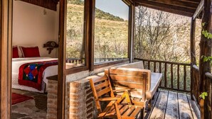 Una stanza accogliente con un letto, una panca in legno e vista su un paesaggio collinare.
