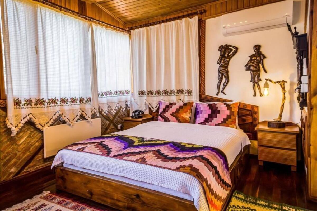 A cozy bedroom with a wooden bed, patterned curtains, and decorative wall art.