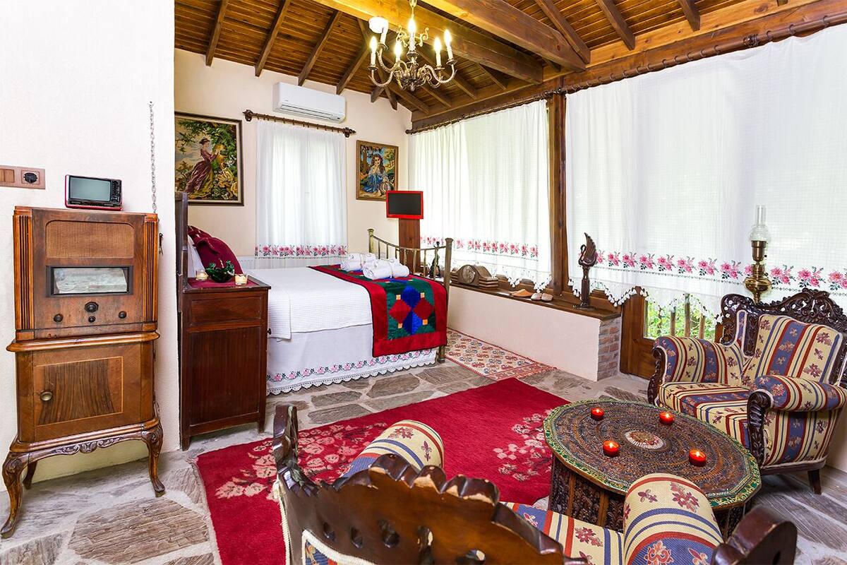 A traditional room with a bed, wooden furniture, a chandelier, and a view of the outdoors.