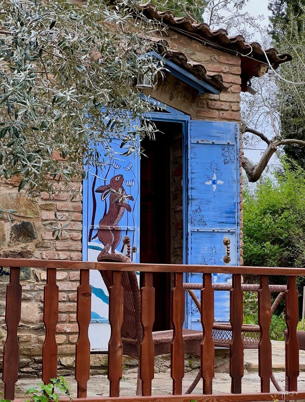 A rustic stone building with a blue door and a wooden balcony railing.