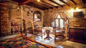 Una stanza rustica con pareti in mattoni a vista, travi in legno, un camino in pietra, un tavolo da pranzo in legno e una televisione montata a parete.