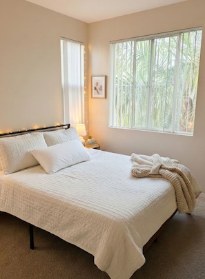 A bedroom with a large bed, two bedside tables, a nightstand, a window with blinds, and a framed picture on the wall. - One Bedroom Apartment Marina Del Rey (Marina del Rey)
