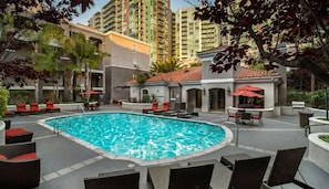 A swimming pool surrounded by lounge chairs and tables, with tall buildings in the background. - One Bedroom Apartment Marina Del Rey (Marina del Rey)