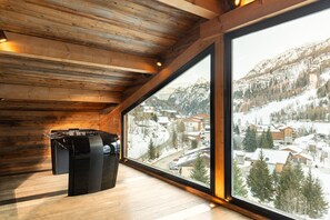 A wooden interior with a large window overlooking a snowy village. - Quezac Chalet • Pool, sauna, hot tub • 16 people (Tignes)