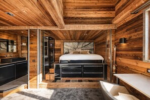 A modern bedroom with a wooden ceiling, a large bed, a built-in bench, and a glass shower enclosure. - Quezac Chalet • Pool, sauna, hot tub • 16 people (Tignes)
