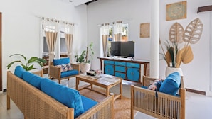 A spacious living area with wicker furniture, a flat-screen TV, and decorative wall art. - Canggu Wave Villa (Canggu)