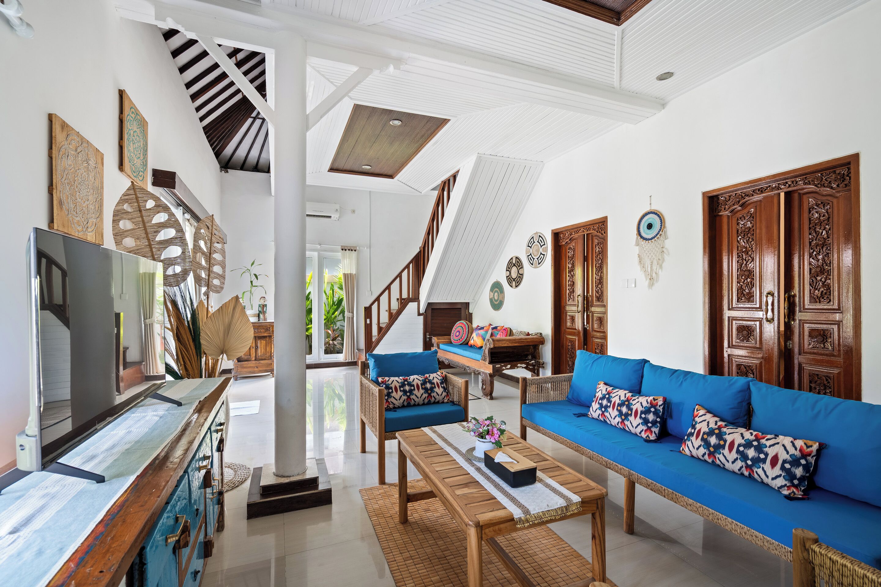 A spacious living area with a large blue sofa, wooden coffee table, and a television on a wooden cabinet.