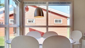 En modern inredning med ett stort fönster, vita, runda bord och stolar.