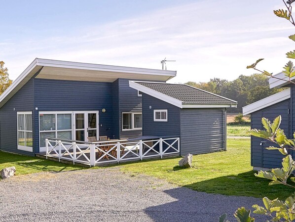 Een modern huis met twee verdiepingen, een overdekte veranda en een grindpad.