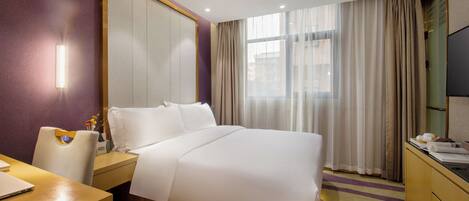 Una habitación de hotel con cama, escritorio, silla, televisión y ventana con cortinas.
