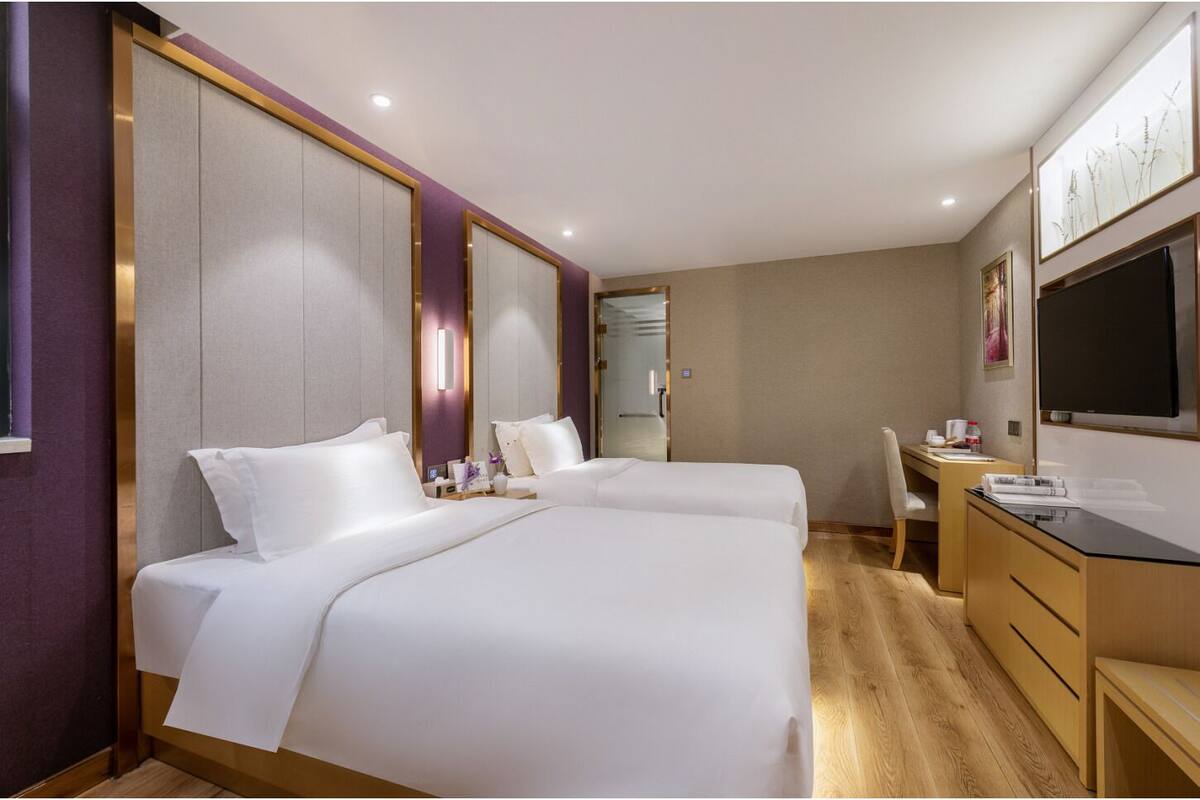 A hotel room with two beds, a desk, a chair, and a large mirror.