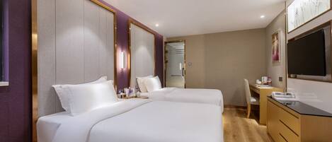 A hotel room with two beds, a desk, a chair, and a large mirror.
