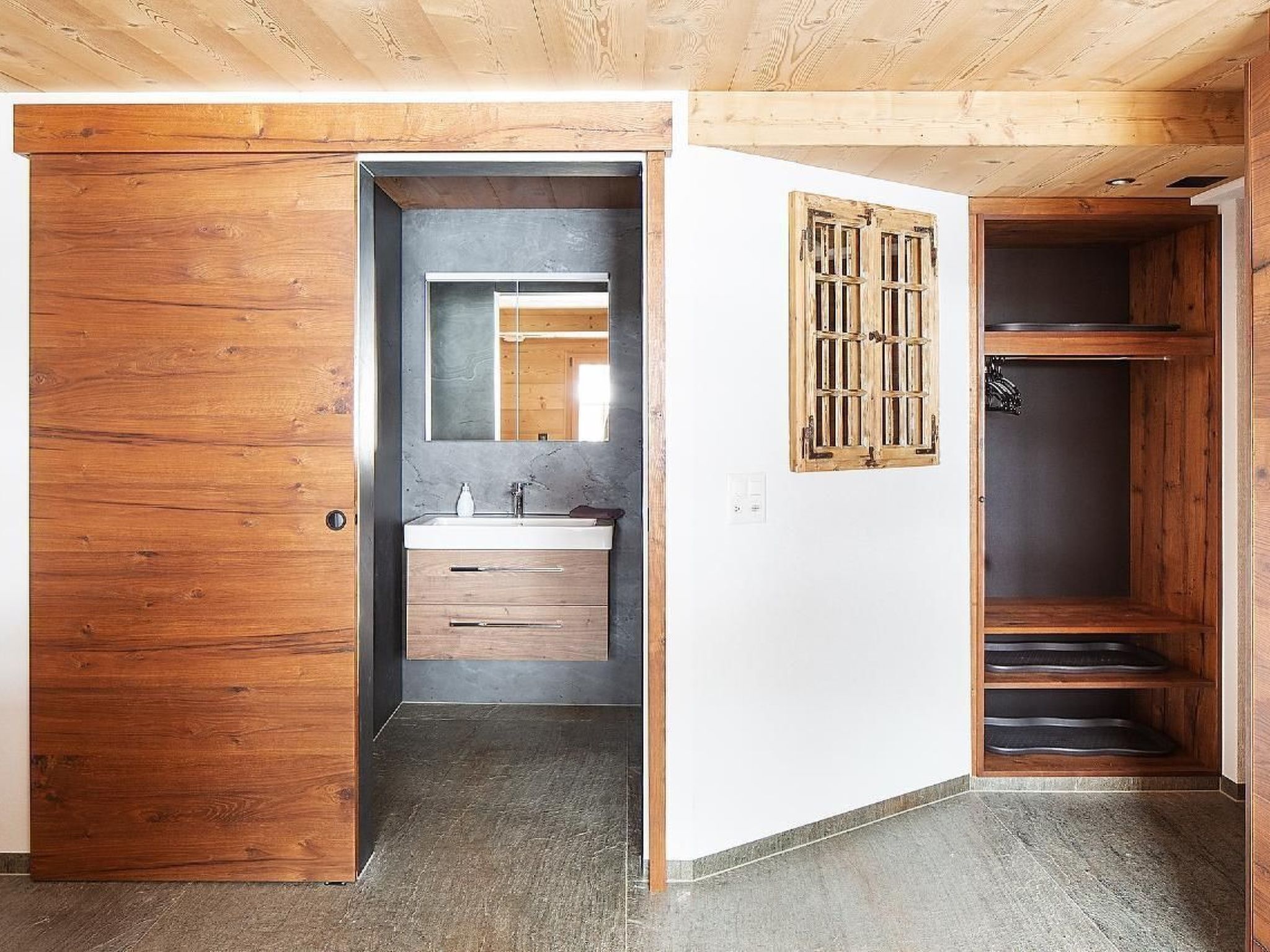 Ein modernes Badezimmer mit Holztür, Waschbecken mit Spiegel und Duschbereich mit Holztür.