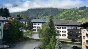 Zona residencial con edificios de varios pisos, un estacionamiento y montañas al fondo.