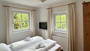 A room with two beds, a TV, and windows with curtains. - Kitzresidenz 11 von Alpinresort Kaprun by Interhome (Kaprun)