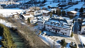 A snow-covered village with traditional buildings, a river, and mountains in the background. - Kitzresidenz 11 von Alpinresort Kaprun by Interhome (Kaprun)