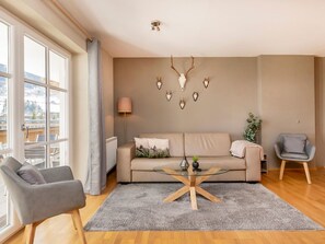 Ein modernes Wohnzimmer mit einem Sofa, einem Glastisch und einem grauen Sessel.