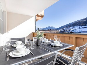 Ein Esstisch, gedeckt mit weißen Tellern, Schüsseln und Gläsern, mit Blick auf eine verschneite Berglandschaft.