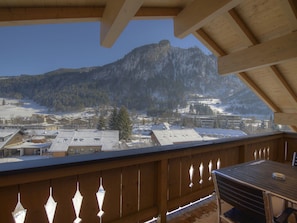 Ein Balkon mit Blick auf einen verschneiten Berg und eine darunterliegende Stadt.