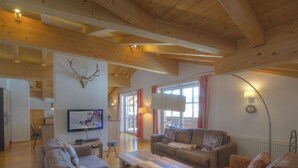 A spacious living room with wooden beams, a television, a sofa, and a coffee table. - Penthouse Alpinresort Kaprun oben 14 by Interhome (Kaprun)