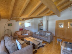 Ein gemütliches Wohnzimmer mit Holzbalken, zwei Sofas, einem Couchtisch und einem Fernseher.