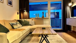 En stue med sofa, sofabord og udsigt til en balkon.