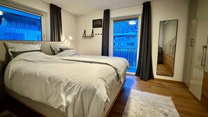 Et soveværelse med en stor seng, et spejl, et klædeskab og udsigt til en balkon.