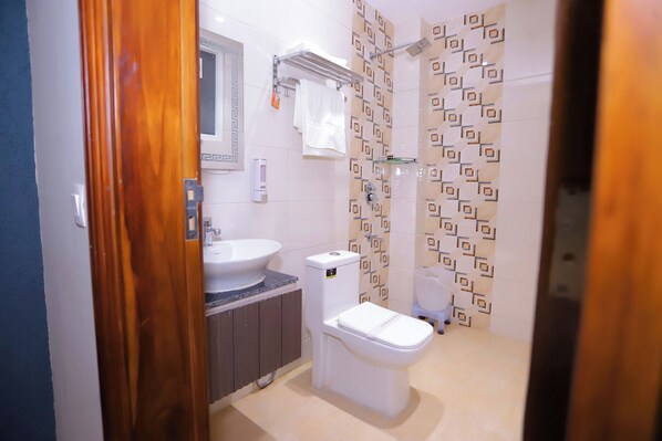 A modern bathroom with a sink, toilet, and shower. - Hotel Nirvana Inn Near Expo Center (Greater Noida)