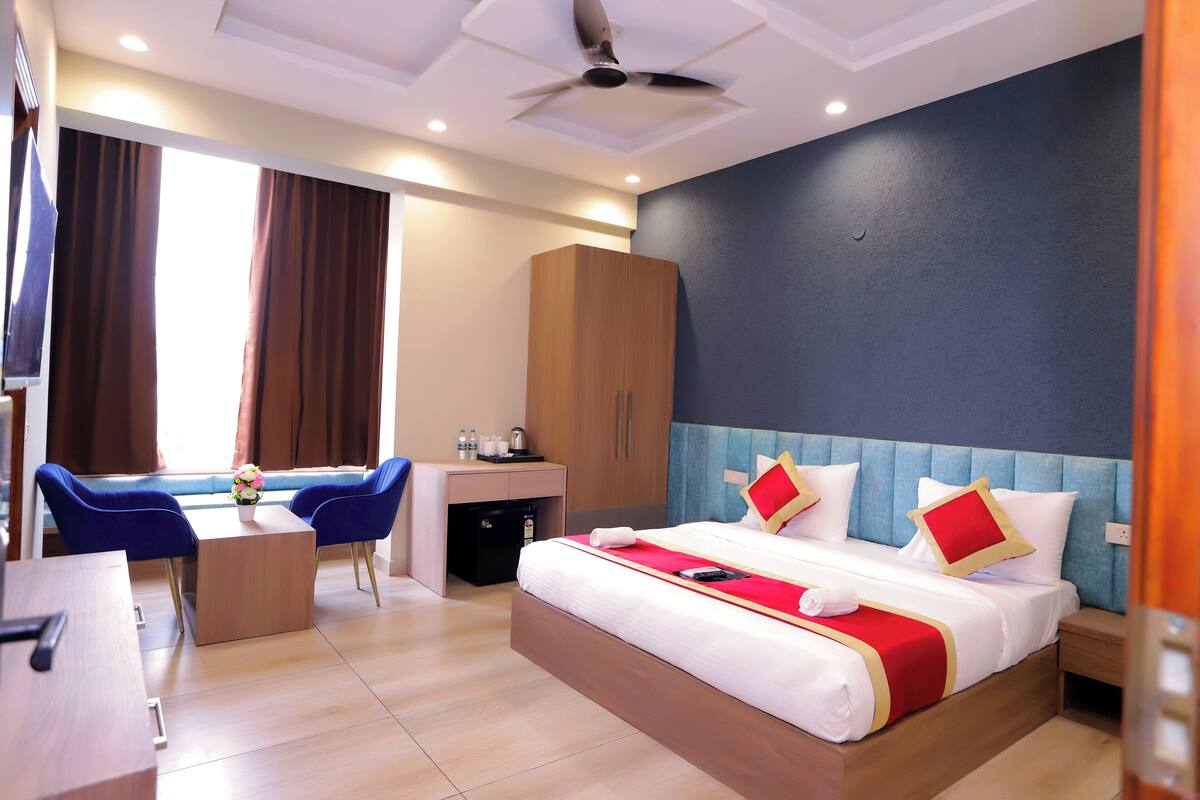 A hotel room with a bed, bedside table, nightstand, desk, chair, and wardrobe.