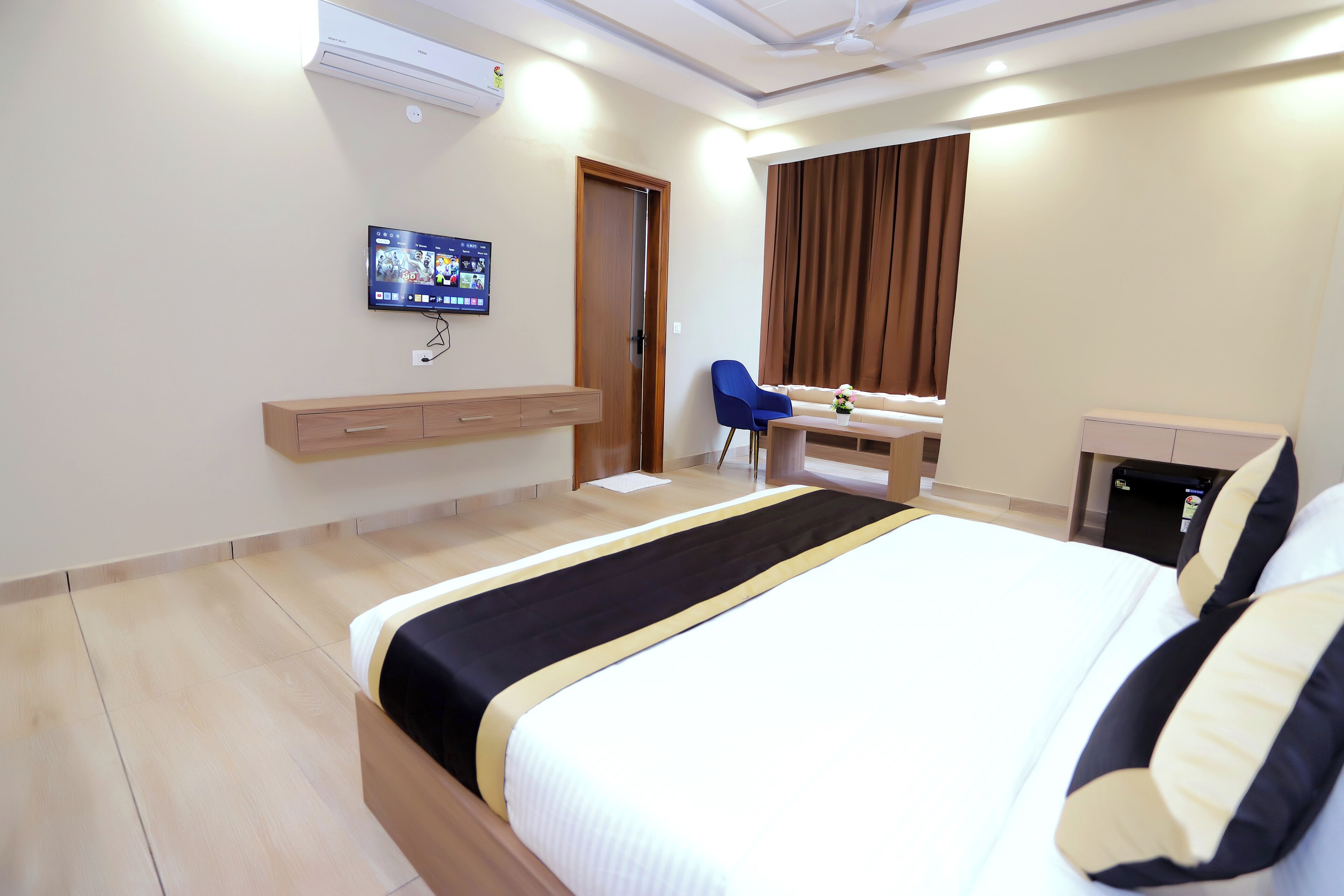 A hotel room with a bed, a desk, a chair, a TV, and a wardrobe.
