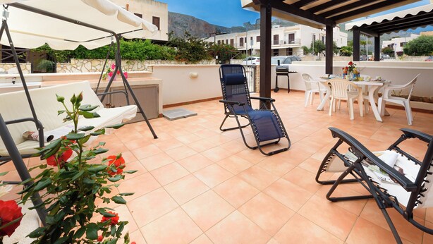 Eine Terrasse mit Schaukel, Tisch und Stühlen sowie einer Pergola.
