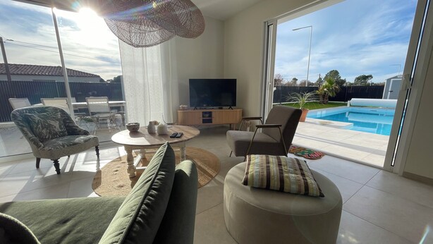 Una sala de estar moderna con un sofá, un sillón, un reposapiés y un televisor.