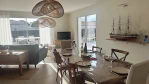 Un comedor con una mesa dispuesta para seis personas, un televisor y un modelo de barco en la pared.