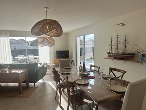 A dining area with a table set for six, a television, and a ship model on the wall. - Villa "La marine" with garden, terrace and swimming pool (Les mathes)