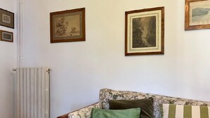 A room with a radiator, a floral-patterned sofa with cushions, and framed pictures on the wall. - Chalet Bazzi by Interhome (Brissago)